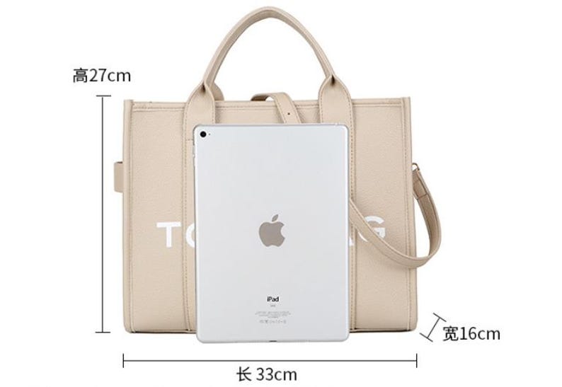 Pu&ograve; includere: Borsa tote beige con manico superiore e tracolla staccabile. La borsa &egrave; lunga 33 cm, alta 27 cm e larga 16 cm. Sulla borsa &egrave; stampata la scritta "TOG". Un iPad &egrave; posizionato davanti alla borsa.