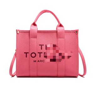 May include: A pink tote bag with a top handle and a shoulder strap. The bag has the word "TOTE" and "MARC" printed on the front. The bag is made of a smooth material and has a rectangular shape.