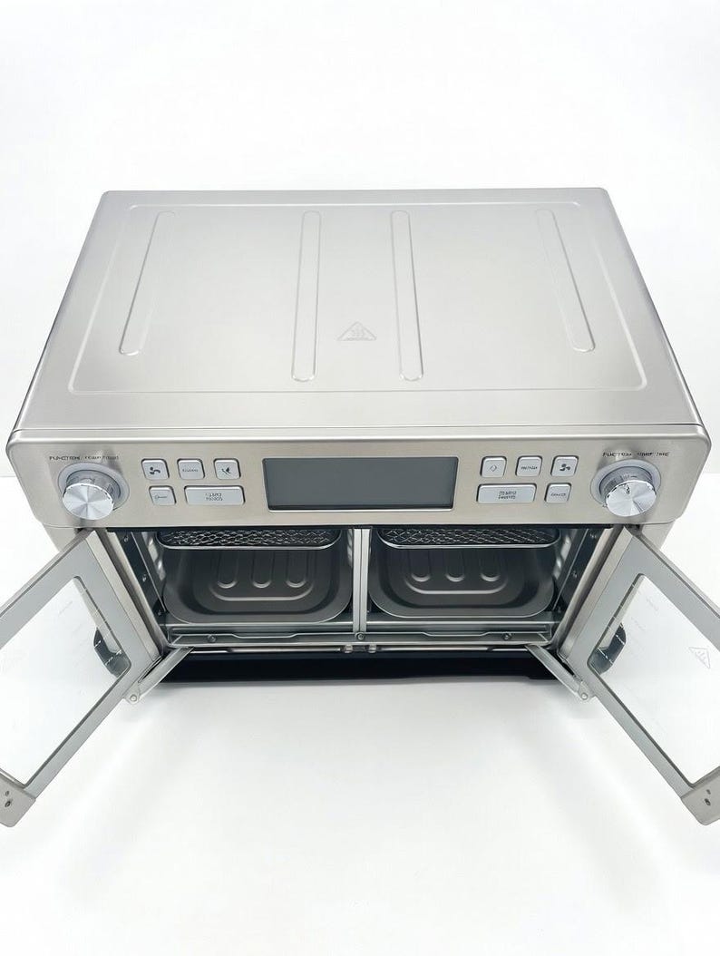 May include: A stainless steel air fryer oven with two pull-down doors. The appliance has a digital display and control knobs. The interior reveals two cooking baskets. The doors are clear, allowing a view of the interior.