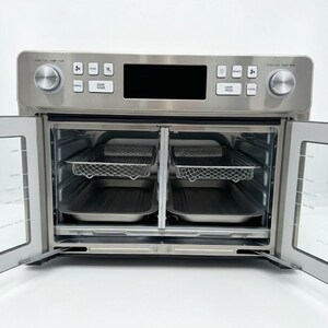 May include: A stainless steel air fryer oven with the doors open, revealing two wire racks and two trays. The control panel has a digital display and several buttons and dials. The oven is on a white surface.