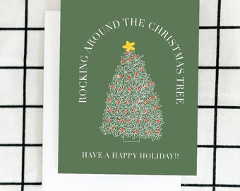May include: A green Christmas card with a white outline of a Christmas tree with red ornaments and a yellow star on top. The text "Rocking Around The Christmas Tree" is in a white arc above the tree. The text "Have a Happy Holiday!" is below the tree.