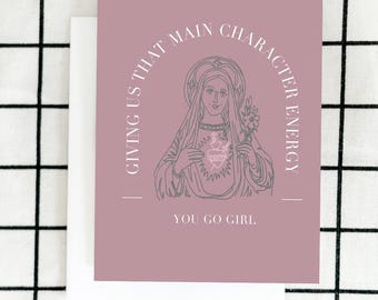 May include: A pink card with a gray line drawing of a woman with a heart in her hands. The text on the card reads "Giving us that main character energy. You go girl."