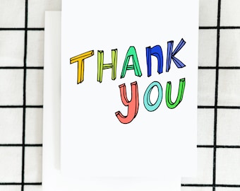 May include: A white card with the words "Thank You" written in colorful, outlined letters. The letters are in different colors, including red, orange, yellow, green, blue, and purple.