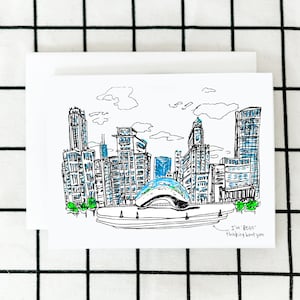 May include: A black and white line drawing of the Chicago skyline, including the Cloud Gate sculpture, also known as "The Bean". The drawing is on a white card with the text "I've Bean thinking about you" written in black.