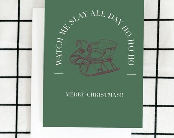 May include: A green Christmas card with a red illustration of a sleigh. The card reads "WATCH ME SLAY ALL DAY HO HO HO" and "MERRY CHRISTMAS!!" on a white background.