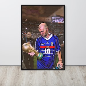 Op de afbeelding: Een ingelijste poster met een gestileerde illustratie van een voetballer in een blauw shirt met het nummer 10, die een gouden trofee vasthoudt. De speler is afgebeeld in een stadion met een menigte op de achtergrond.