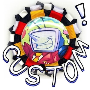 May include: A circular rosette badge featuring a central button with a cartoon character that has a television for a head, wearing a red suit and yellow tie. The rosette is constructed from pleated black, white, red, and gold ribbons.