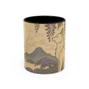 May include: A ceramic coffee mug with a black interior and a wraparound illustration. The design features a full moon, a mountain, a fox, and wisteria in shades of beige, purple, and green. The mug is cylindrical and has a white exterior.