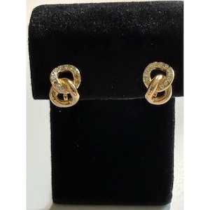 Puede incluir: Un par de pendientes de botón en tono dorado con un diseño de eslabones entrelazados. Cada pendiente consta de un aro de metal dorado liso y pulido conectado a un aro circular incrustado con pequeños brillantes blancos transparentes.