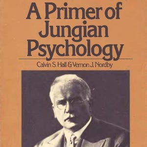 以下が含まれることがあります： カルビン・S・ホールとバーノン・J・ノードビーによる「A Primer of Jungian Psychology」というタイトルの本。表紙は無地のタン色で、濃い茶色の文字と、スーツを着て眼鏡をかけた男性の長方形の白黒写真が中央に配置されています。