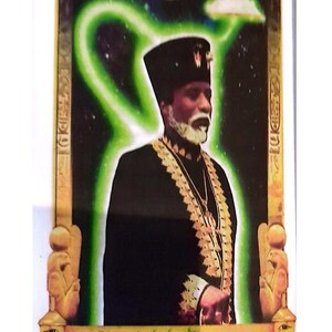 Puede incluir: Retrato de un hombre con t&uacute;nica negra y bordados dorados, con sombrero negro. La imagen tiene un aura verde y el texto "Paa Nabab: Yaanuwn The Master Teacher".