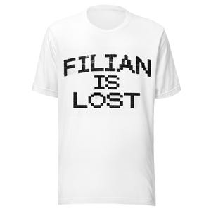 May include: White t-shirt with the text "FILIAN IS LOST" in a pixelated black font. The shirt has a crew neck and short sleeves. The text is centered on the front of the shirt.