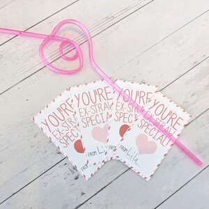May include: Three pink and white Valentine's Day cards with the text "You're Ex-Straw Special" and "From Lila". A pink heart-shaped straw is on top of the cards.