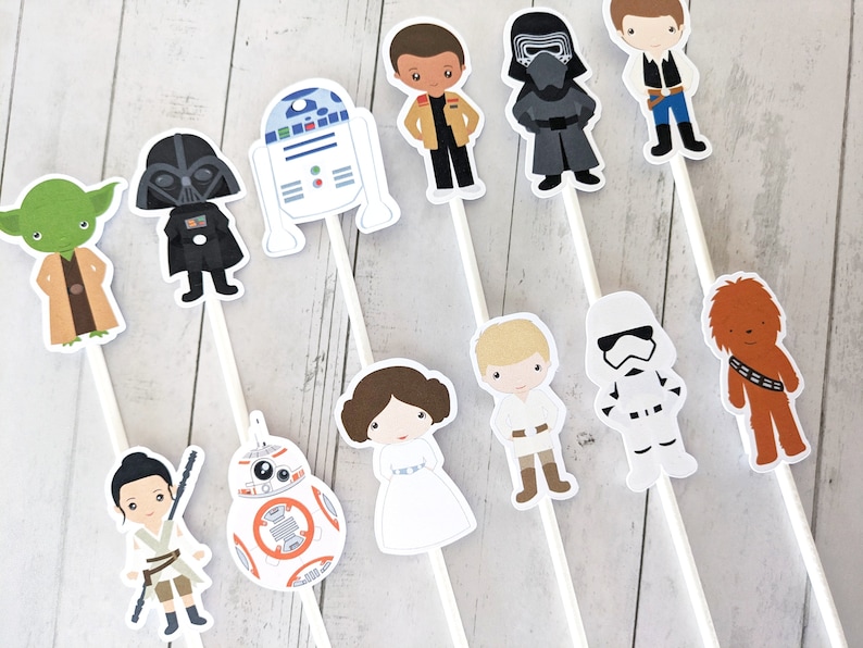 Puede incluir: Un conjunto de 11 adornos para tartas con personajes de Star Wars. Los adornos representan personajes como Yoda, Darth Vader, R2-D2, Chewbacca y un Stormtrooper. Los adornos est&aacute;n impresos en cartulina blanca y unidos a palos blancos.