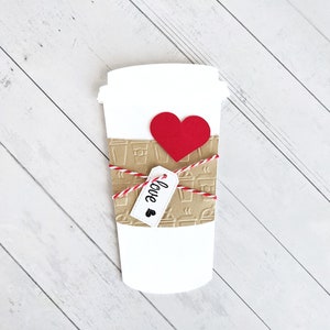 Puede incluir: Un vaso de caf&eacute; de papel blanco con una manga de papel marr&oacute;n decorada con vasos de caf&eacute; y vapor. El vaso est&aacute; atado con una cuerda roja y blanca y tiene un coraz&oacute;n rojo y una etiqueta que dice "love" adjunta.