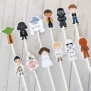 Puede incluir: Conjunto de 12 adornos para tartas de personajes de Star Wars. Los adornos representan personajes como Darth Vader, Yoda, R2-D2, Chewbacca, y muchos m&aacute;s. Los adornos est&aacute;n impresos en cartulina blanca y unidos a palos blancos.
