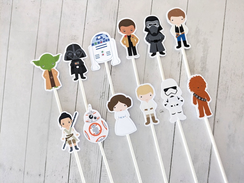 Puede incluir: Conjunto de 12 adornos para tartas de personajes de Star Wars. Los adornos representan personajes como Darth Vader, Yoda, R2-D2, Chewbacca, y muchos m&aacute;s. Los adornos est&aacute;n impresos en cartulina blanca y unidos a palos blancos.