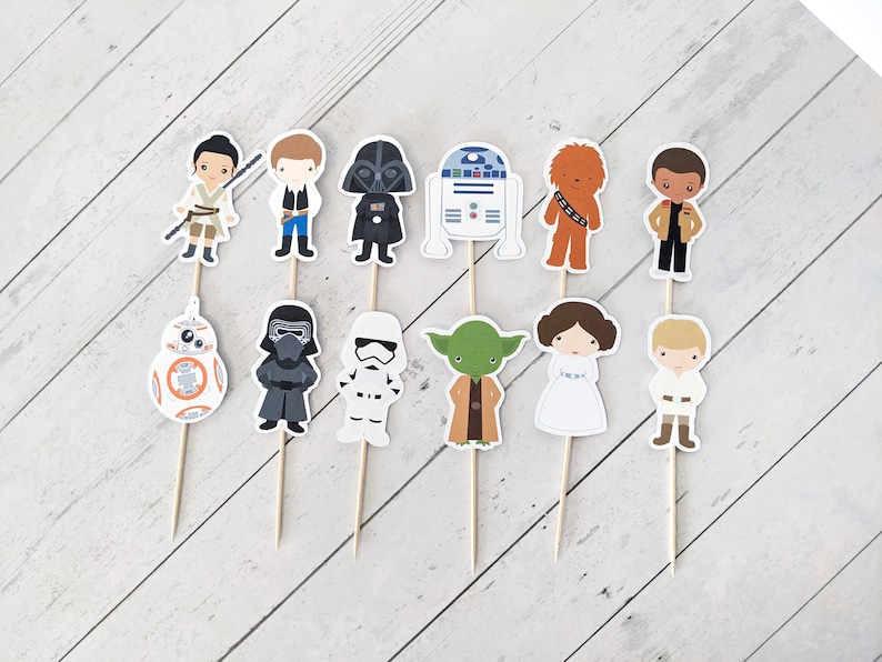 Puede incluir: Conjunto de 12 adornos para tartas de personajes de Star Wars. Los adornos representan personajes como Darth Vader, Yoda, la princesa Leia, Chewbacca y R2-D2. Los adornos est&aacute;n impresos en cartulina y unidos a brochetas de madera.