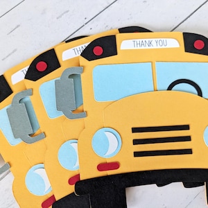 May include: Yellow school bus-shaped cards with black and red details. The cards feature light blue windows and grey side mirrors. Each card has the words "THANK YOU" printed at the top. The cards are arranged in a fan shape.