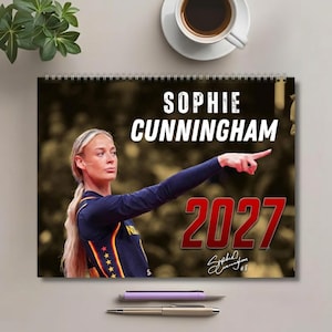 Pode incluir: Um calendário de parede com espiral apresentando uma fotografia da jogadora de basquete Sophie Cunningham em uma camisa azul-escura com detalhes em amarelo e vermelho. O texto diz SOPHIE CUNNINGHAM e 2027, com uma assinatura e o número 8.