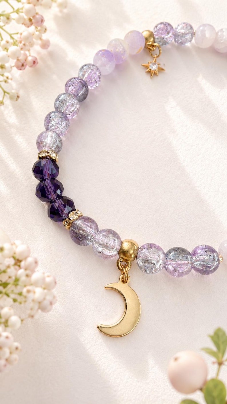 May include: A beaded bracelet featuring light purple crackle glass beads, deep purple faceted crystal beads, and gold-toned spacers. The bracelet includes a gold-toned crescent moon charm and a small gold-toned star charm with a central crystal.