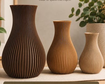 Pode incluir: Três vasos impressos em 3D com uma textura canelada vertical, dispostos em ordem decrescente de tamanho. Os vasos são coloridos em tons de castanho escuro, castanho médio e bege claro. O texto diz RIBBED VASE, MADE WITH PLA e 3 SIZES.