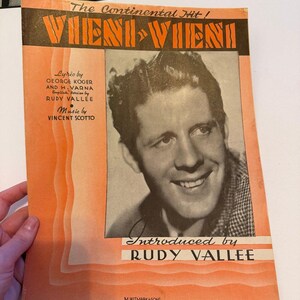 May include: A vintage sheet music cover for the song Vieni-Vieni, featuring a black and white portrait of Rudy Vallee. The orange cover includes the text The Continental Hit, lyrics by George Koger and H. Varna, and music by Vincent Scotto.