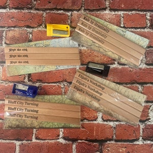 May include: Three sets of wooden pencils with personalized engravings. The first set says "Made by Granddaddy" on each pencil. The second set says "Magic Idea Stick" on each pencil. The third set says "Elijah's Workshop" on each pencil.