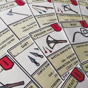 May include: A collection of fantasy-themed game cards featuring illustrations of weapons such as a battle axe, crossbow, and darts. The cards have a beige background with black text and red accents.