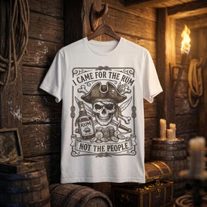 Puede incluir: Una camiseta blanca de manga corta con un estampado gráfico marrón oscuro de una calavera pirata con parche y sombrero, una botella de ron y un cofre del tesoro. El texto dice I CAME FOR THE RUM NOT THE PEOPLE en un marco decorativo.
