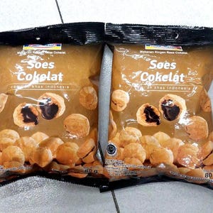 May include: Two identical 80g bags of chocolate cream puffs. The brown packaging features the text Soes Cokelat, images of the round pastries with visible dark chocolate filling, and the Indomaret logo at the top centre of each bag.
