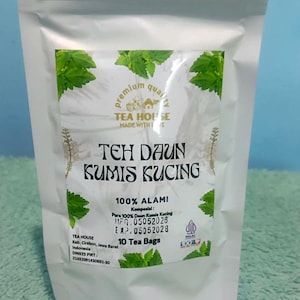 May include: A white stand-up pouch containing 10 tea bags of Teh Daun Kumis Kucing. The label features green leaf illustrations, the text "Premium Quality," "Tea House," "100% Alami," "10 Tea Bags," and manufacturing and expiration dates of 05052026 and 05052028.