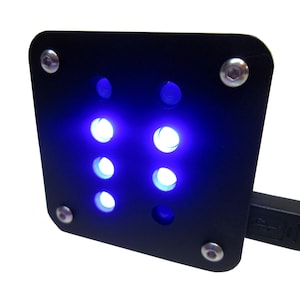 May include: A black square-shaped device with a USB connector and six blue LED lights shining through circular holes.