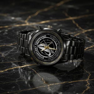 Könnte beinhalten: Eine schwarze Armbanduhr aus Metall mit einem runden Zifferblatt, das in der Mitte das Logo Starfleet Command United Federation of Planets zeigt. Die Uhr hat goldfarbene Zeiger, ein schwarzes Gliederarmband und Ziffern am äußeren Rand.