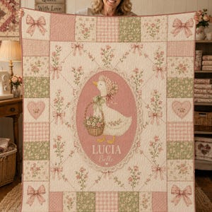 May include: A patchwork quilt featuring a central oval medallion with a white duck wearing a bonnet and carrying a flower basket. The text reads LUCIA Belle. The quilt has pink and green floral patterns, gingham squares, and pink bows.