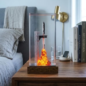 Peut inclure: Maquette décorative de fusée dans un boîtier en acrylique transparent. La fusée noire et blanche décolle d'une plateforme avec une base orange et jaune flamboyante. La base en bois porte l'inscription "STARSHIP".