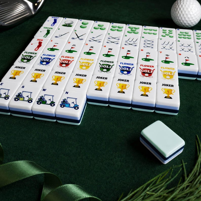 May include: A set of white rectangular mahjong tiles featuring golf-themed graphics, including golf clubs, golf carts, trophies, and numbered flags. Each tile has a smooth finish with colorful printed designs and a blue and white layered base.