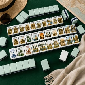 K&ouml;nnte beinhalten: Ein Set rechteckiger Mahjong-Spielsteine mit hellgr&uuml;nen R&uuml;ckseiten und wei&szlig;en Vorderseiten, die Illustrationen von Pyramiden, Kamelen, Palmen und Entdeckern zeigen. Einige Steine sind mit Texten wie Joker, Flower, Soap und Red Dragon beschriftet.