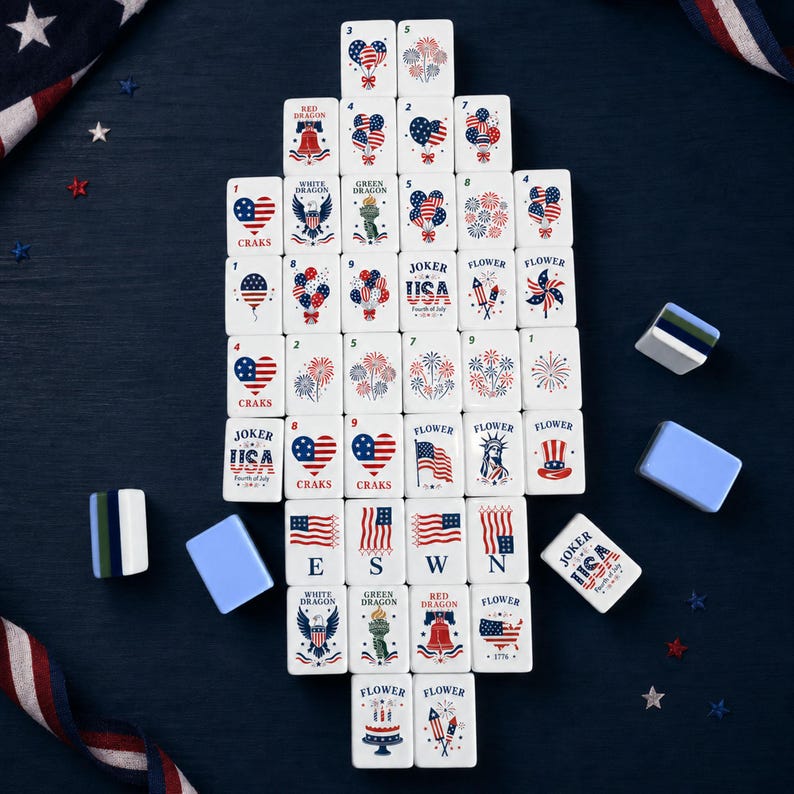 May include: A set of white mahjong tiles featuring red, white, and blue patriotic designs including American flags, fireworks, hearts, eagles, the Statue of Liberty, and text reading Joker USA Fourth of July, arranged in a vertical rectangular formation.