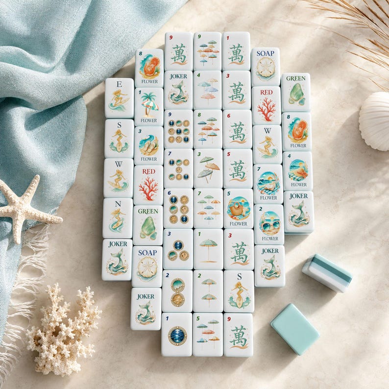 May include: A set of white rectangular mahjong tiles featuring colorful illustrations of mermaids, beach umbrellas, coral, seashells, and soap, alongside traditional Chinese characters and numbers. Two plain tiles are placed separately nearby.