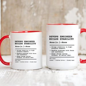 May include: Two white ceramic mugs with bright red handles and interiors. Each mug features black printed text that defines a DevOps Engineer as someone who builds stability, including the name Rose and three numbered points describing professional traits.