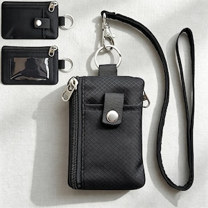 May include: A black rectangular pouch with a grid pattern, featuring a side zipper, a front pocket with a snap button closure, and a detachable lanyard with a metal lobster clasp and ring. Two smaller matching pouches are shown in the upper left corner.