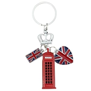 Könnte beinhalten: Ein silberfarbener Schlüsselanhänger mit einer Krone, einer roten Telefonzelle und zwei Anhängern mit der Flagge des Union Jack. Auf dem Anhänger der Telefonzelle steht das Wort "TELEPHONE". Die Anhänger sind rot, weiß und blau.