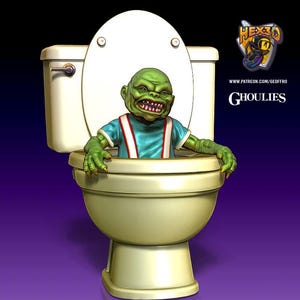 Puede incluir: Una criatura verde con dientes afilados y manos con garras emerge de un inodoro blanco. La criatura lleva una camisa azul con tirantes rojos. El inodoro está sobre un fondo degradado púrpura y negro. El texto dice "GHOULIES".