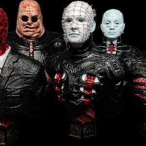 Puede incluir: Una colección de cinco bustos de personajes de terror con texturas faciales detalladas, que incluyen una figura roja con un cigarrillo, una figura calva con gafas oscuras, una figura pálida con alfileres en la cabeza, una figura azul claro y un monstruo rojo texturizado.