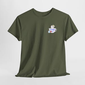 May include: Olive green t-shirt featuring a small graphic of a cat in a teacup with a flower, and the words "Summer Tea". The graphic is in white, blue, and red. The shirt is made of a soft material.