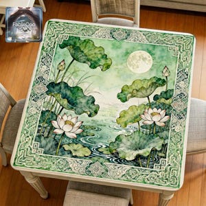 Chinese style green lotus mahjong mat displayed on a square table, featuring blooming lotus flowers, layered lotus leaves, rippling water, a glowing full moon, and an ornate traditional border in elegant jade green tones.