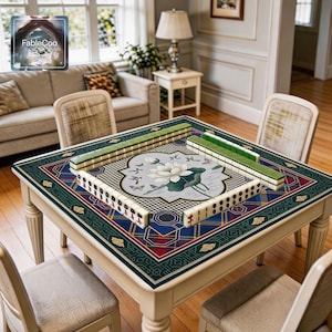 Oriental scenic game mat shown in use with mahjong tiles, highlighting the spacious square playing area, smooth cushioned surface, and elegant artwork featuring a white lotus bloom, birds in flight, butterfly accents, water ripples, and decorative geometric borders in green, blue, wine red, gold, cream, and muted gray.