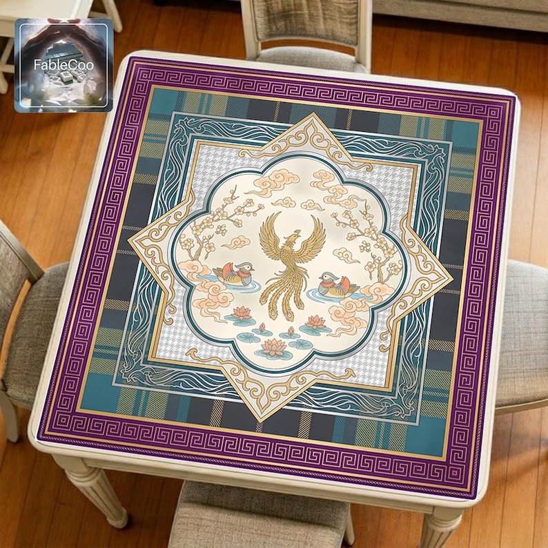 Asian-style mahjong mat displayed on a square home table, featuring an original oriental-inspired design with a central phoenix, paired koi fish, lotus blossoms, soft cloud motifs, flowering branches, and decorative geometric borders in purple, teal blue, gold, peach pink, and ivory tones.