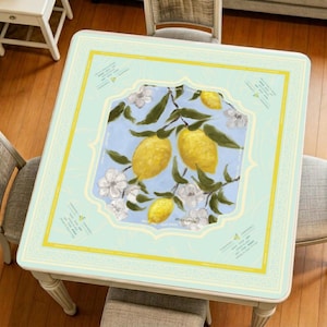 Lemon mahjong mat displayed on a square table, featuring a soft pastel background, bright yellow lemons, white blossoms, and an elegant decorative border for a fresh and artistic look.